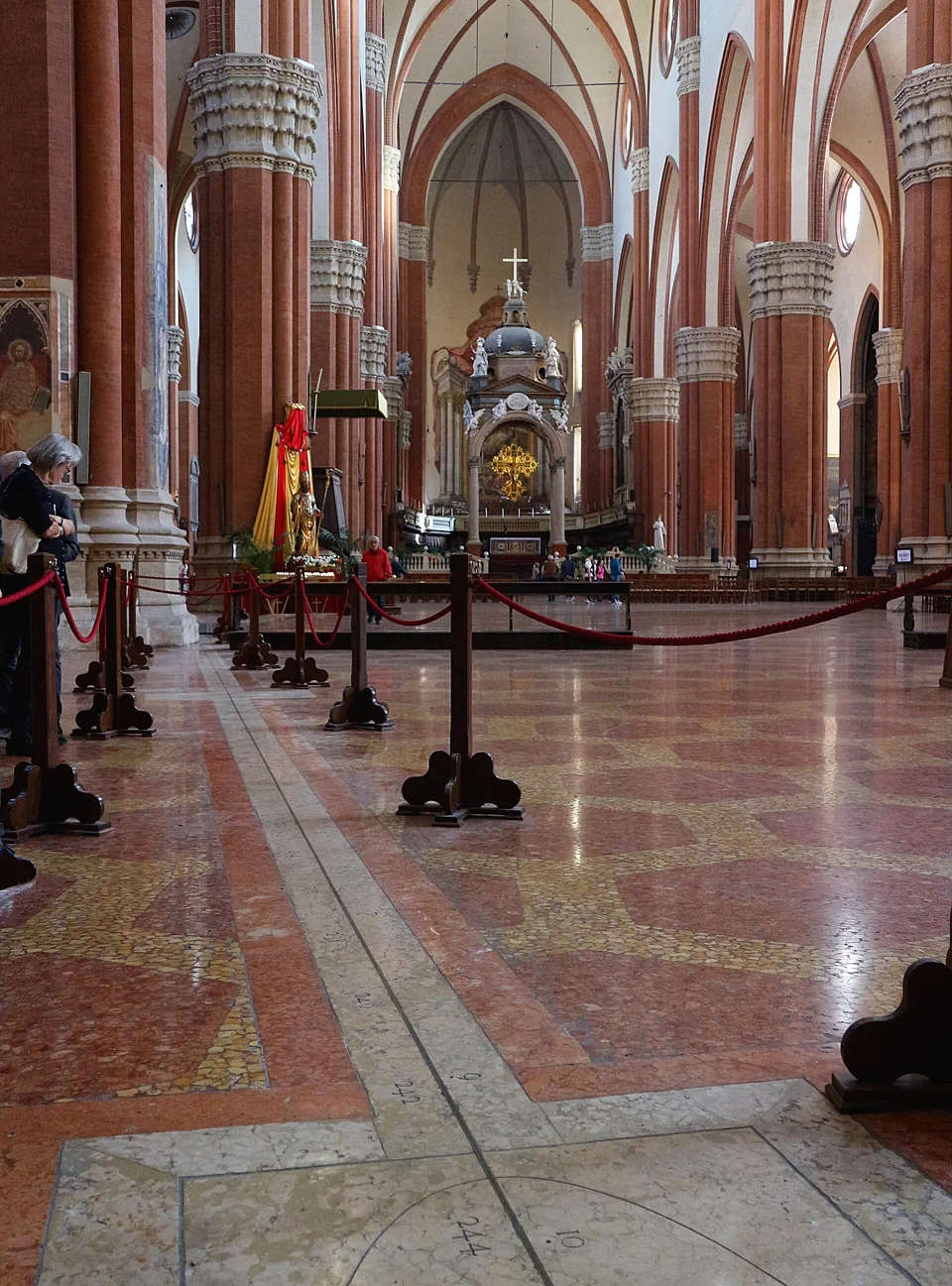A brass meridian line crosses the patterned floor beneath the tall red-brick arches of San Petronio.