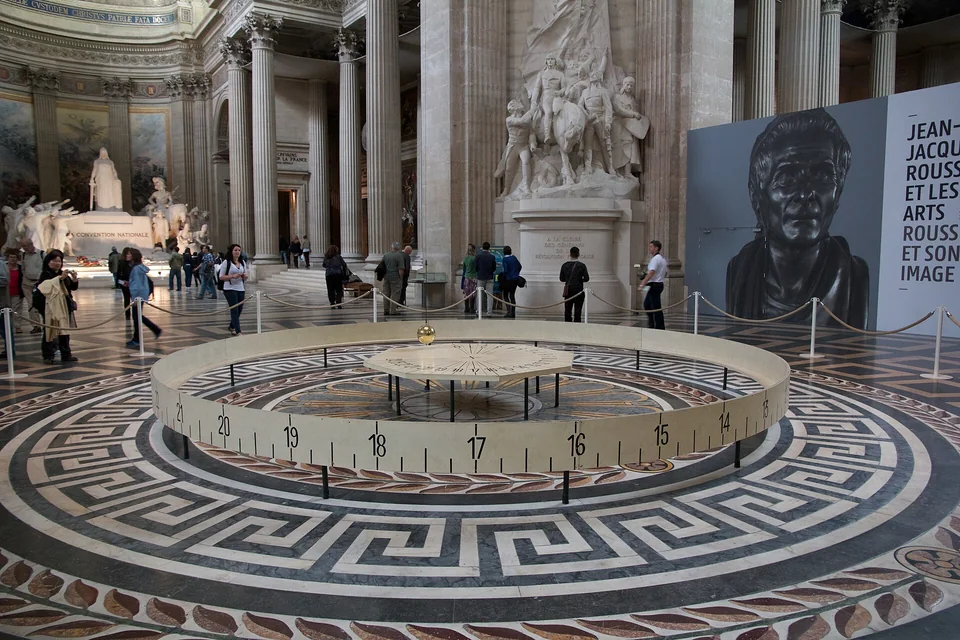 The Foucault pendulum suspended inside the grand interior of the Panthéon in Paris, with its circular floor display below.