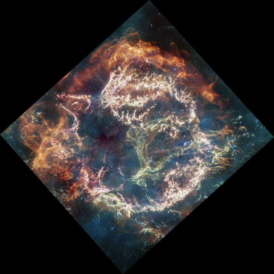 A ring of orange, pink, and green filaments in Webb’s color-mapped infrared image of Cassiopeia A.