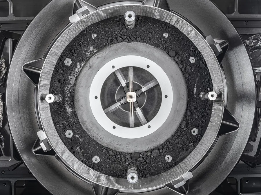 Dark grains and small rocks form a ring inside the opened metal OSIRIS-REx sample collector.