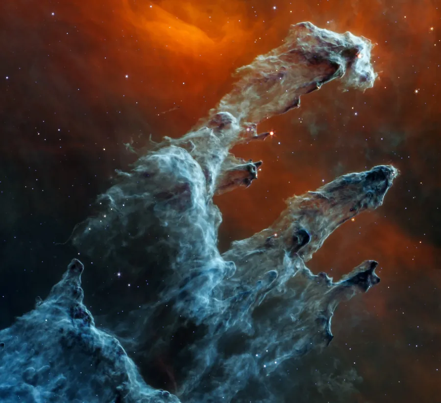 Blue-gray dust pillars rise against a rust-orange background, with only a few bright stars visible.
