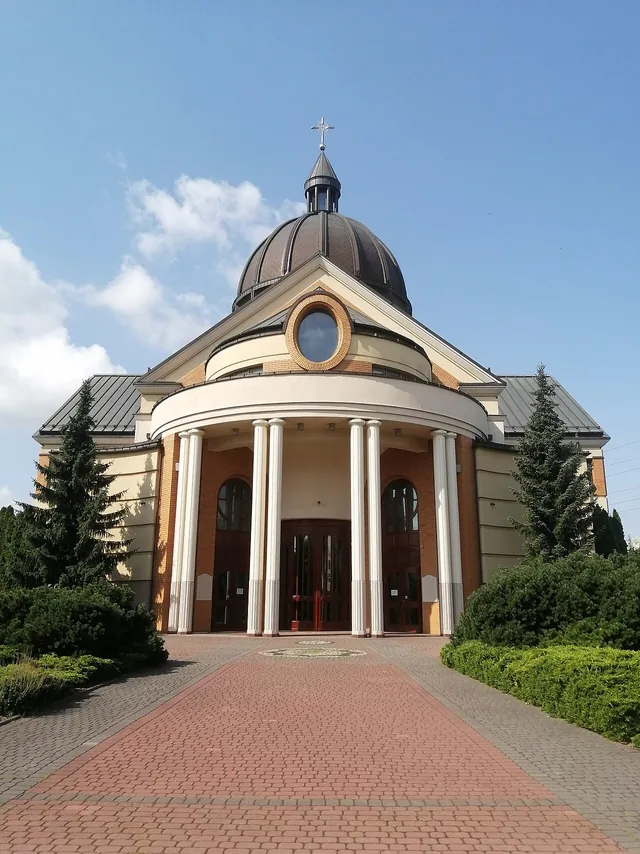 Sunlit exterior of the Church of Saint Anthony Mary Zaccaria in Warsaw, with a domed roof and columned entrance.
