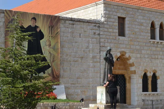 A statue and devotional banner of Charbel Makhlouf at the Saint Maron monastery complex in Annaya, photographed in 2015.