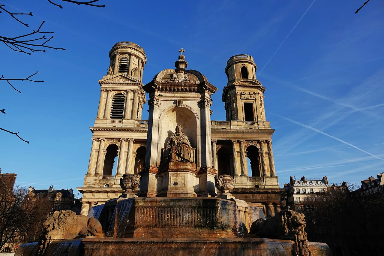 The historic twin-tower facade of Saint-Sulpice church in Paris behind the nineteenth-century fountain.