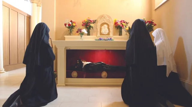 Benedictines of Mary praying beside Wilhelmina Lancaster’s displayed body, in a modified still from TAN Books’ Finding Sr. Wilhelmina (2023). The image documents a devotional presentation, not an anatomical examination or proof of untreated preservation.
